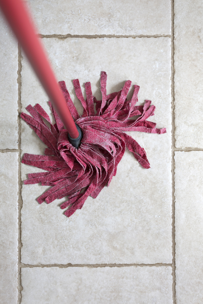 Red kitchen mop being used to clean a floor surface