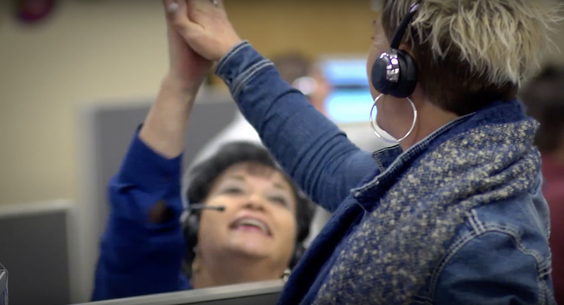 Gold Mountain Communications has partnered with DailyPay to offer its employees instant access to earned wages. An image of two women giving high five.