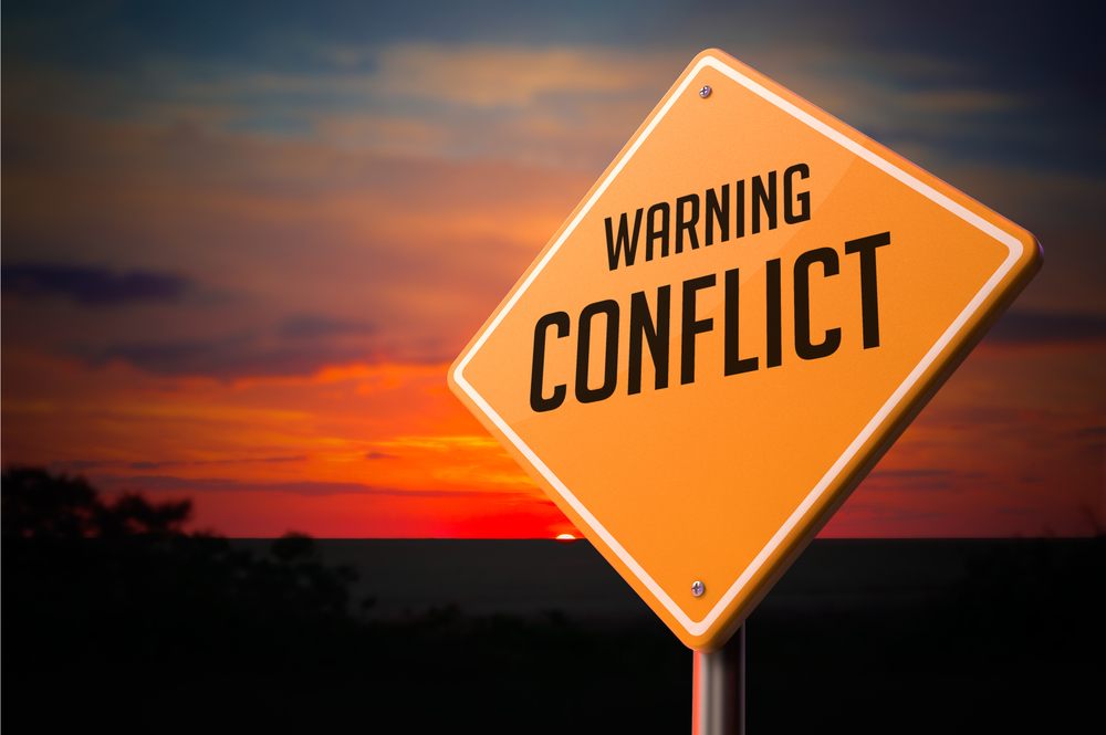 Road sign with "WARNING CONFLICT" and a sunset background. This image illustrates a major obstacle to employee engagement.