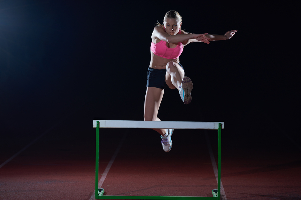 Hurdler leaping over a hurdle. Athletes buy-in and engage with their work because they believe in the mission of their work.
