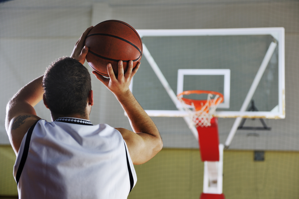 A Recreational basketball player gets ready to shoot on a glass backboard basketball hoop with a torn net. EOS and BITE7 clarify how people are accountable and measured in an organization.