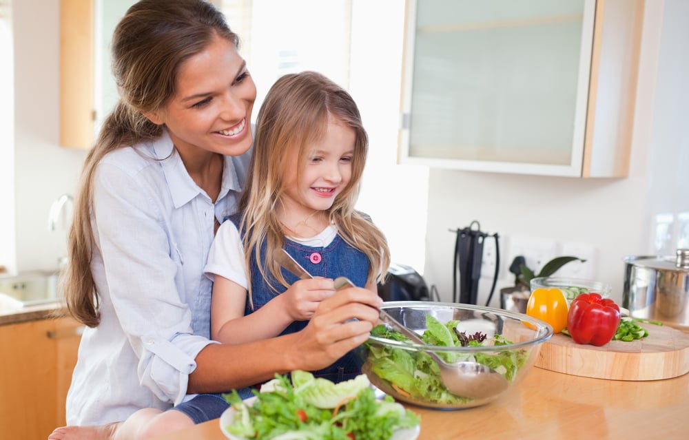 Mother and her daughter preparing a salad in their kitchen