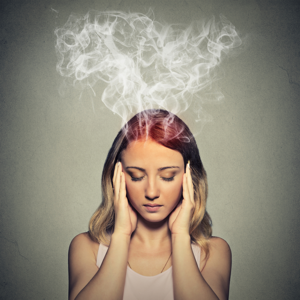 Portrait young stressed woman thinking too hard steam coming out up of head isolated on grey wall background. Face expression emotion perception