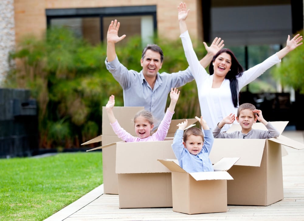 Happy family in cardboard boxes moving house: Tips to Help your Transferee with their move to Sweden