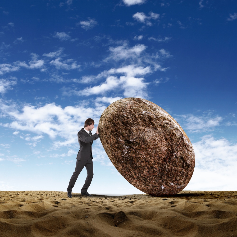 Image of businessman rolling a giant stone.jpeg