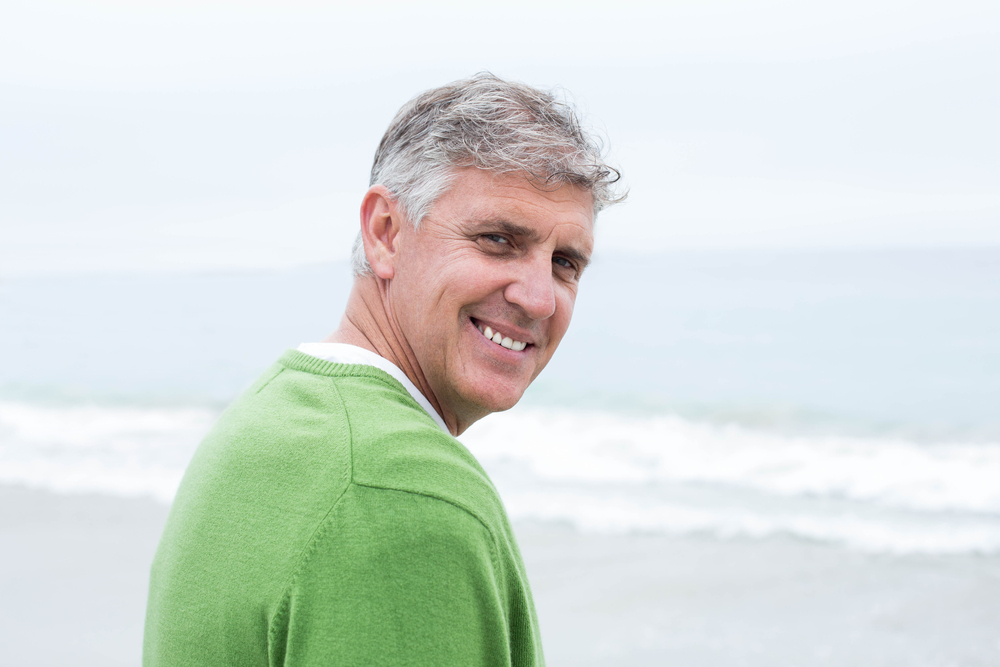 Smiling man standing at the shoreline of the beach