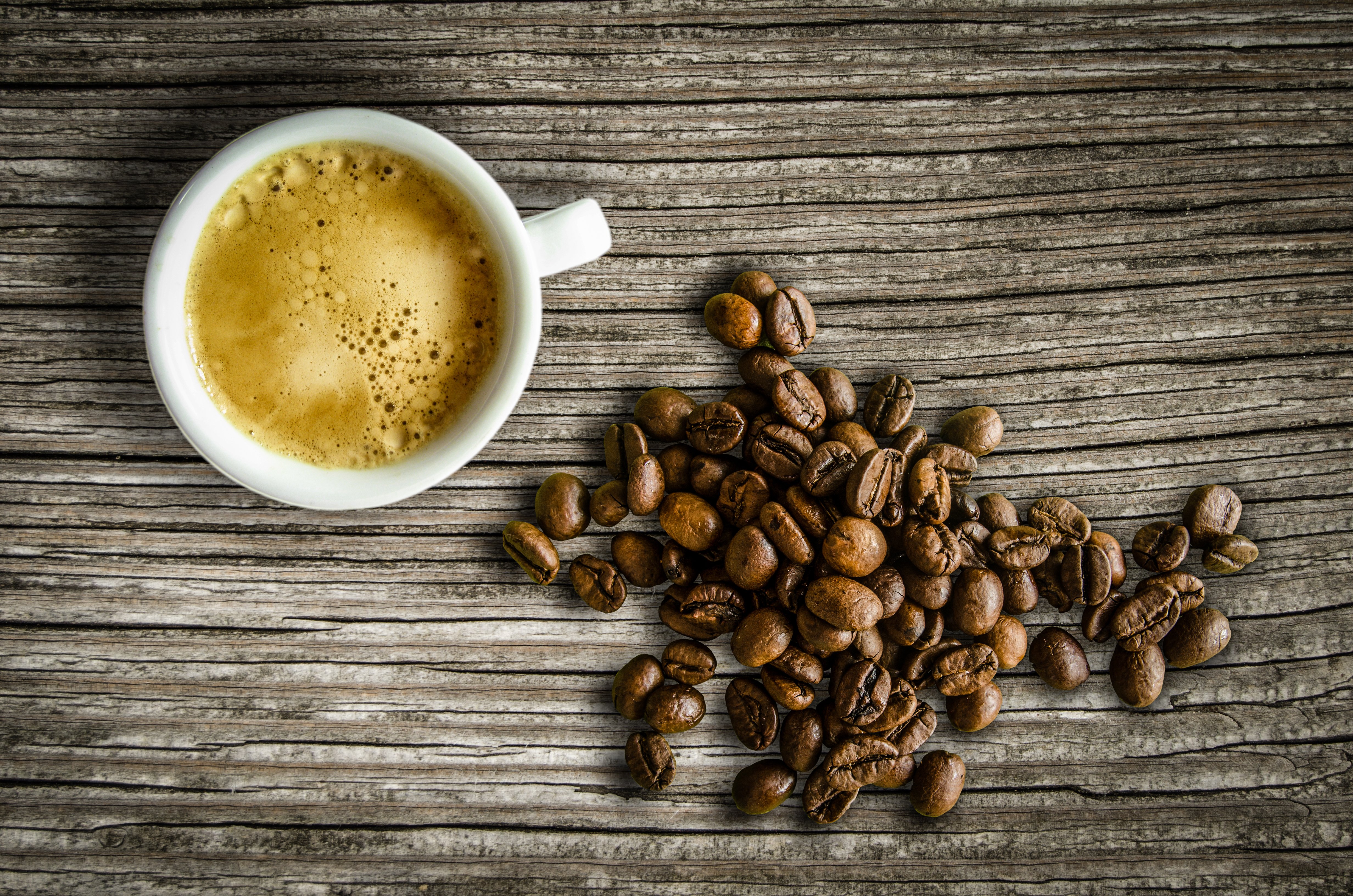Espresso and coffee beans on a wooden background, representing coffee, tea, and chocolate brands that fight human trafficking