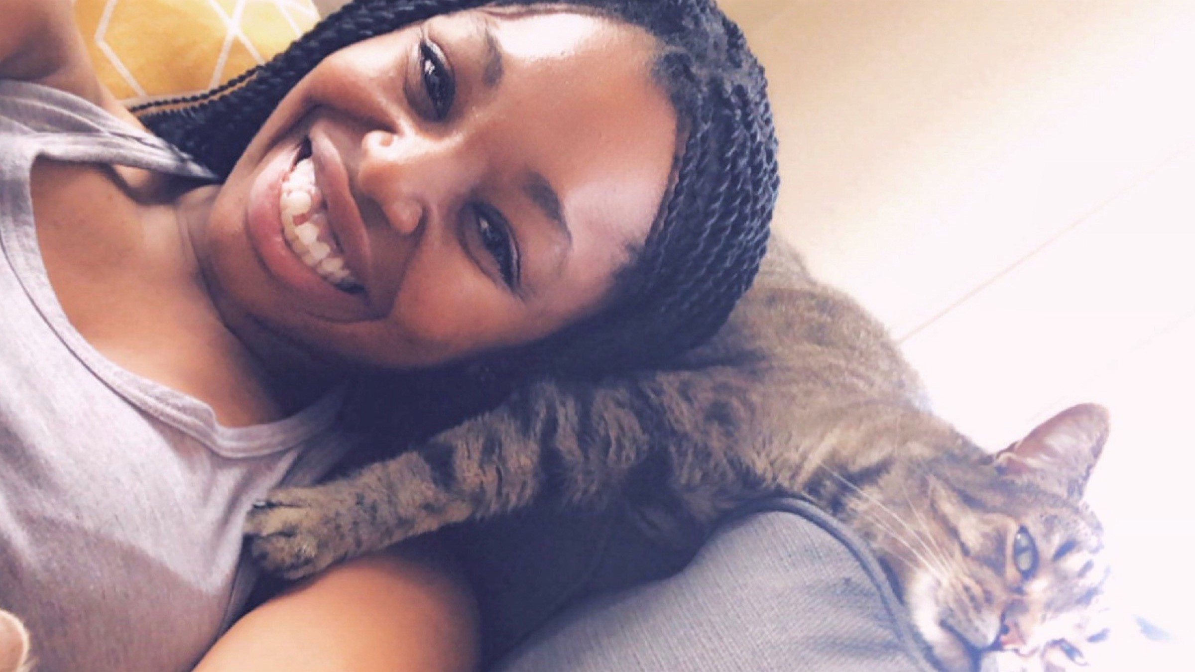 Image of Rachel Jones taking a selfie while laying her head of on pet cat.