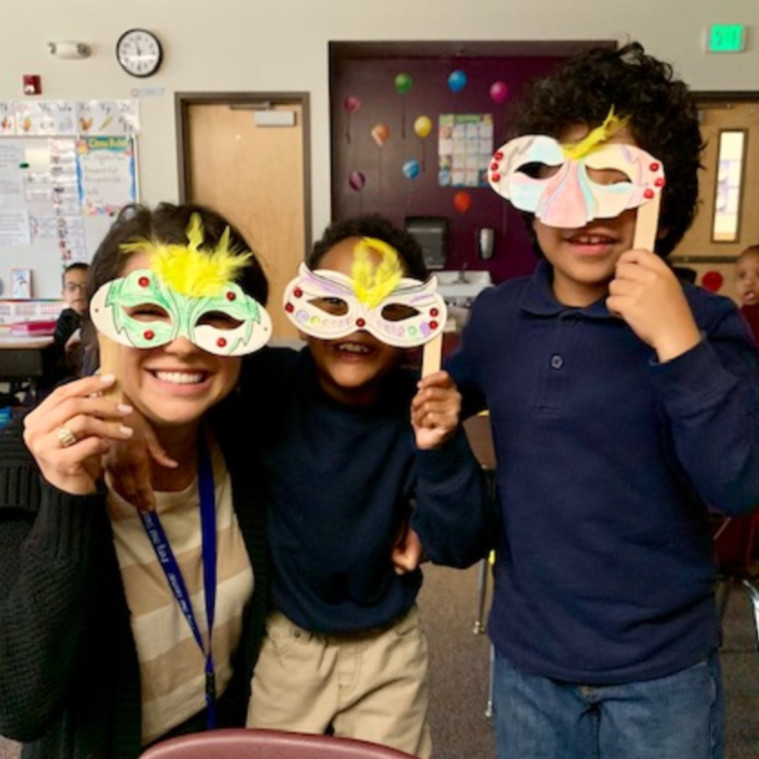 Selfie of Lauren posing with two kids in masks.