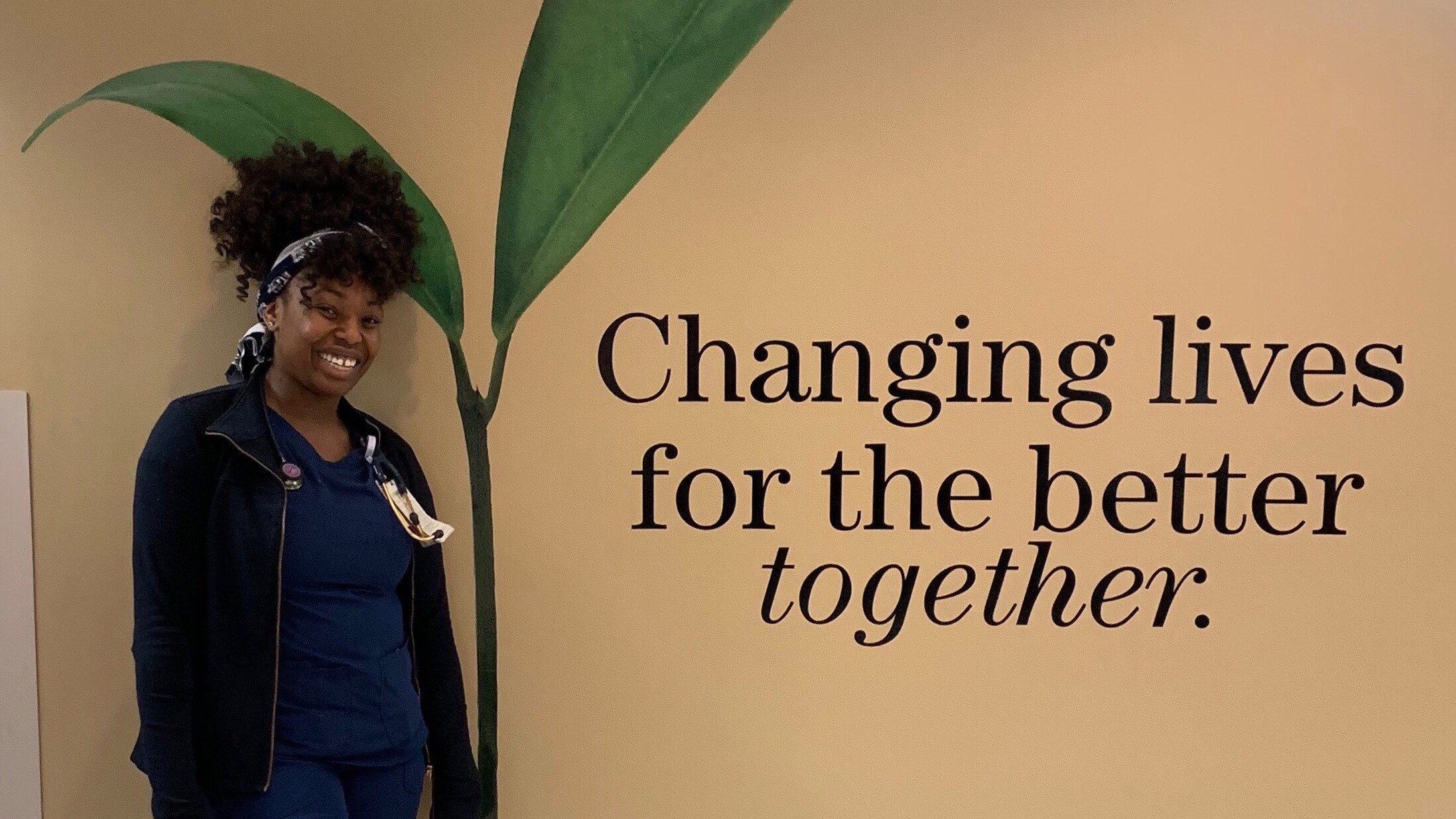 Image of a woman standing next to a large plant, with the caption "Changing Lives for the better together."
