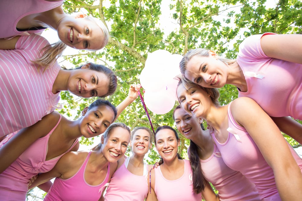 Smiling women in pink for breast cancer awareness on a sunny day