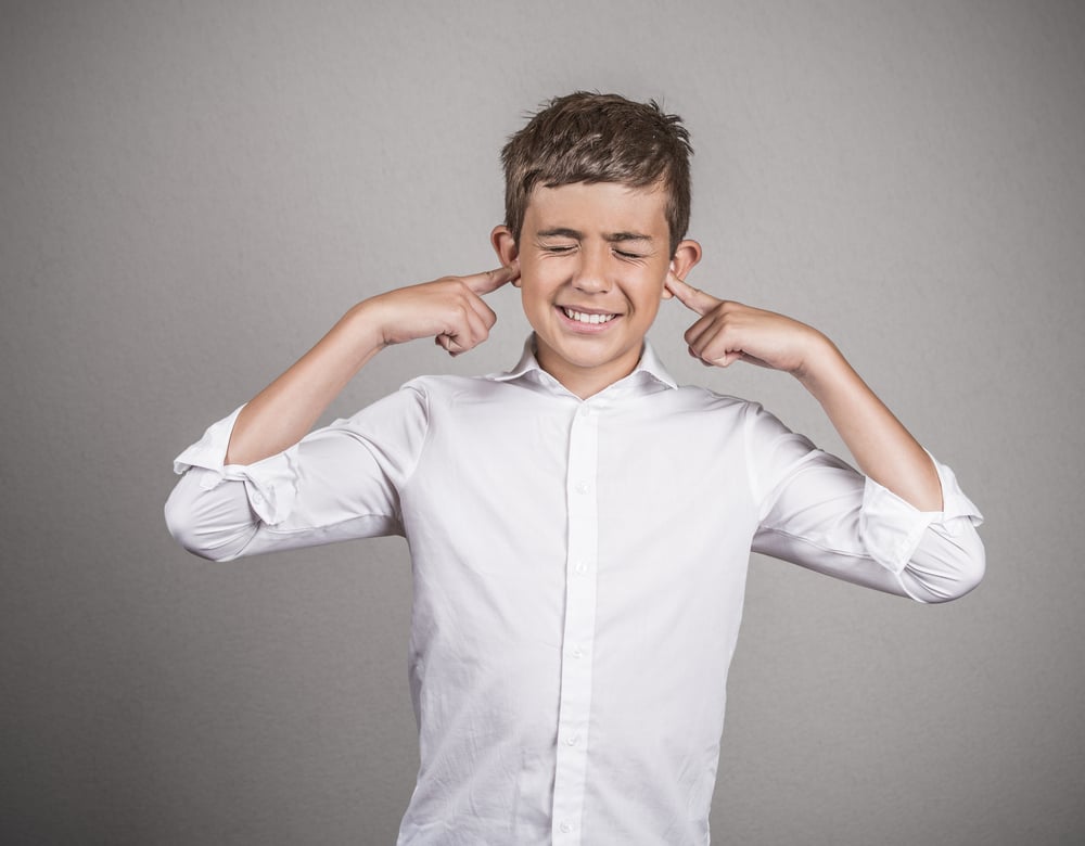 a young boy plugging his ears to not listen