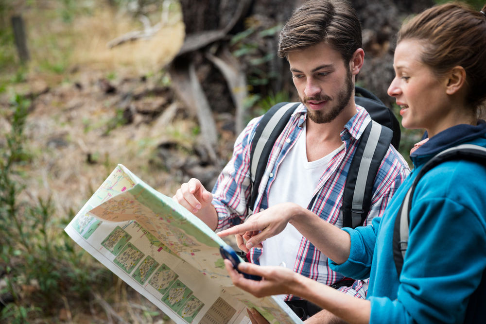 Hiker couple looking at map in forest