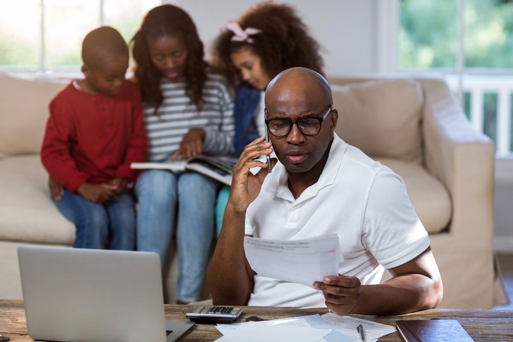 Man talking on mobile phone while checking bills at home