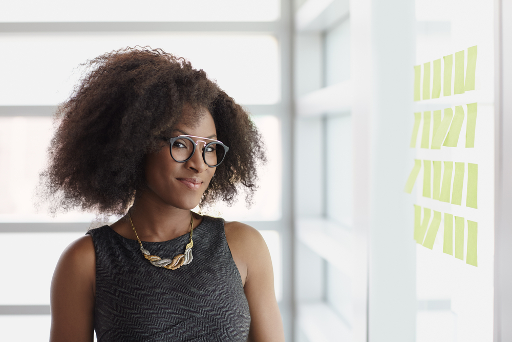 Portrait of a smiling business woman with an afro in bright glass office