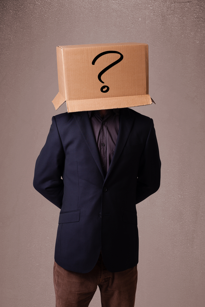 Young man standing and gesturing with a cardboard box on his head with question mark