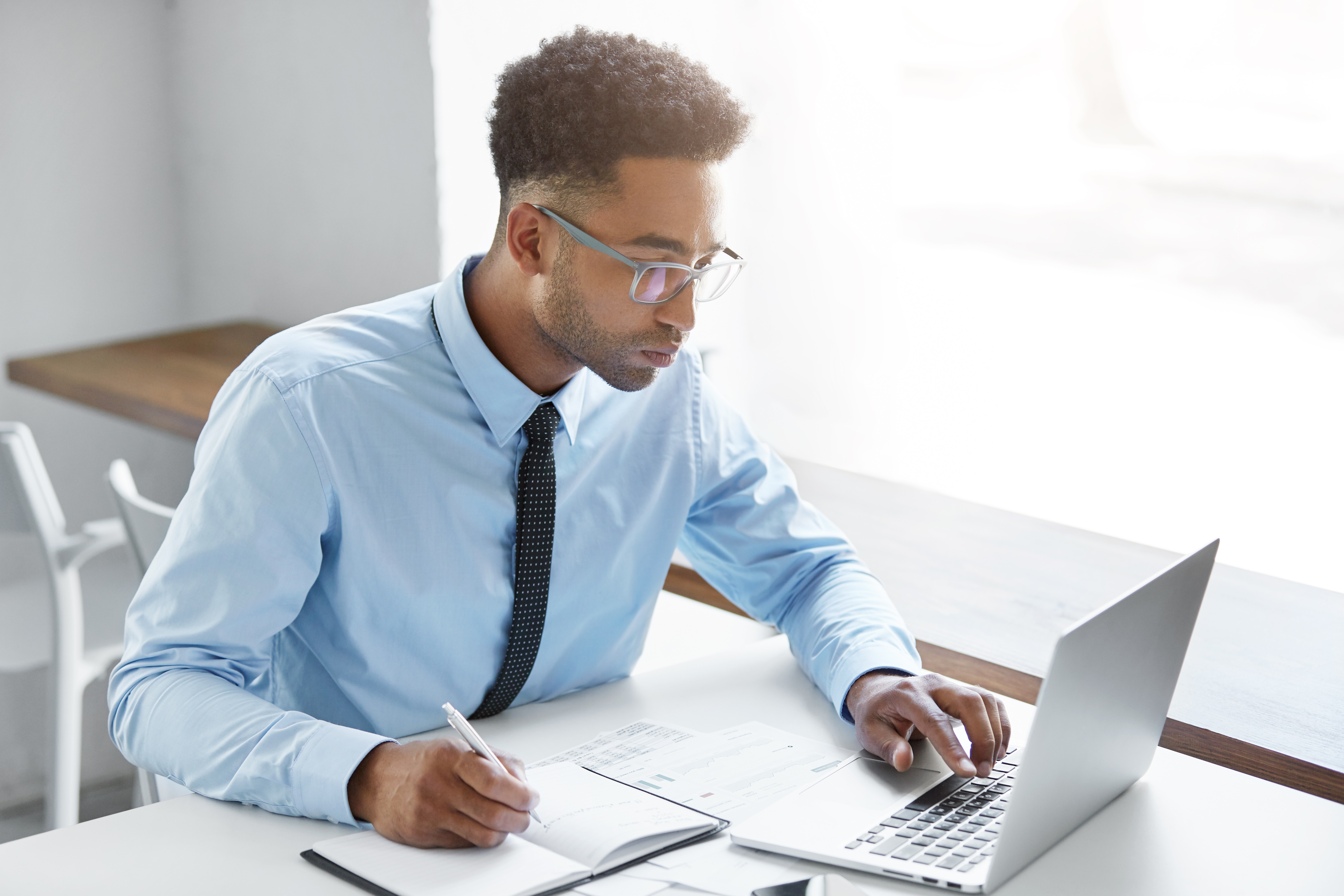 Male worker site in C-style blue shirt at office desk