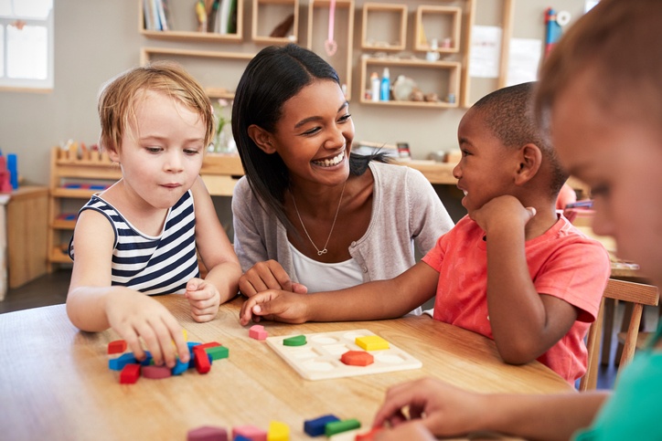 teacher helping autistic kid play with others 