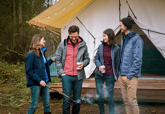 Two couples standing by a fire while glamping at Lake Dale Resort in San Juan Island, Washington