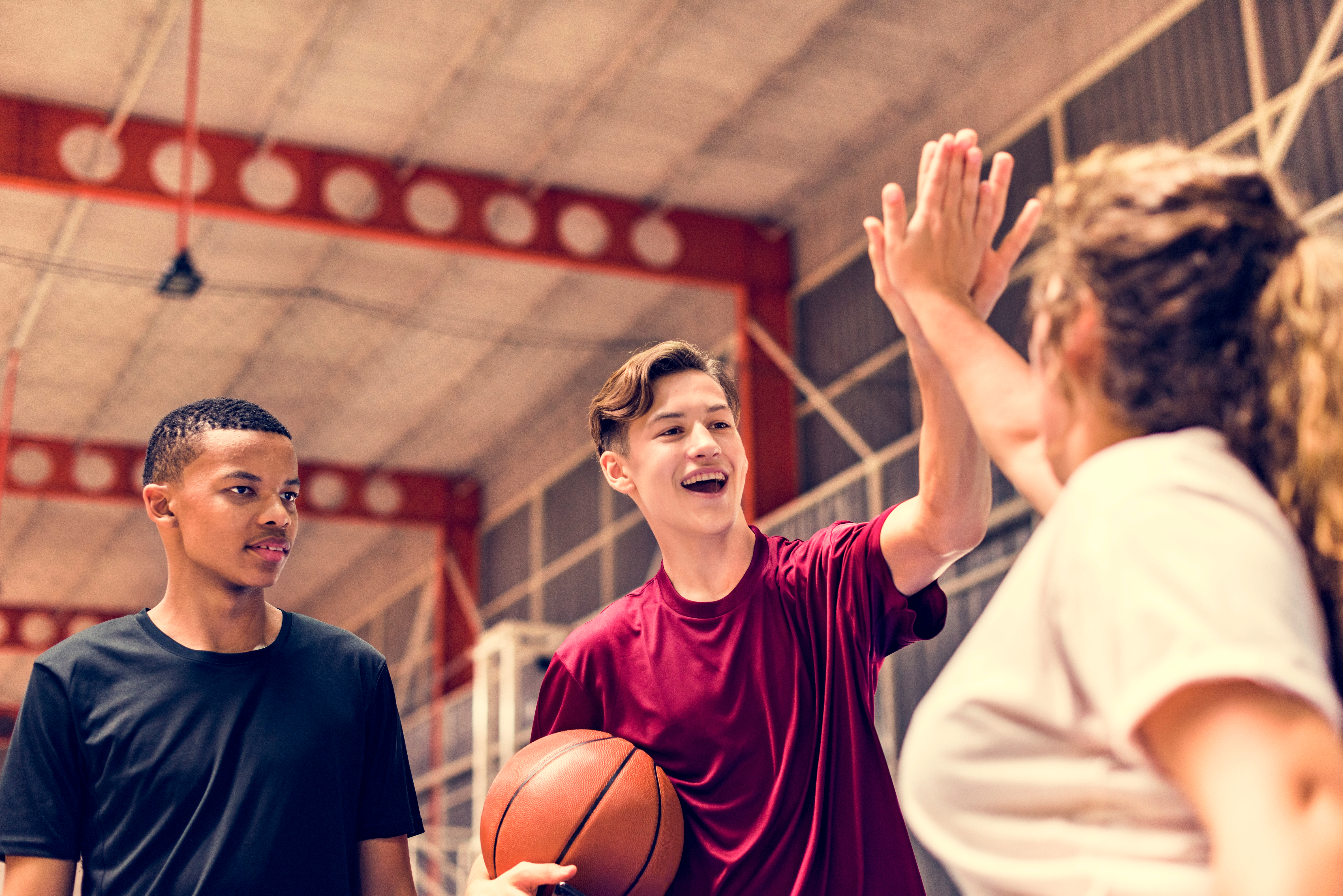 three youth exchanging high-fives after playing basketball