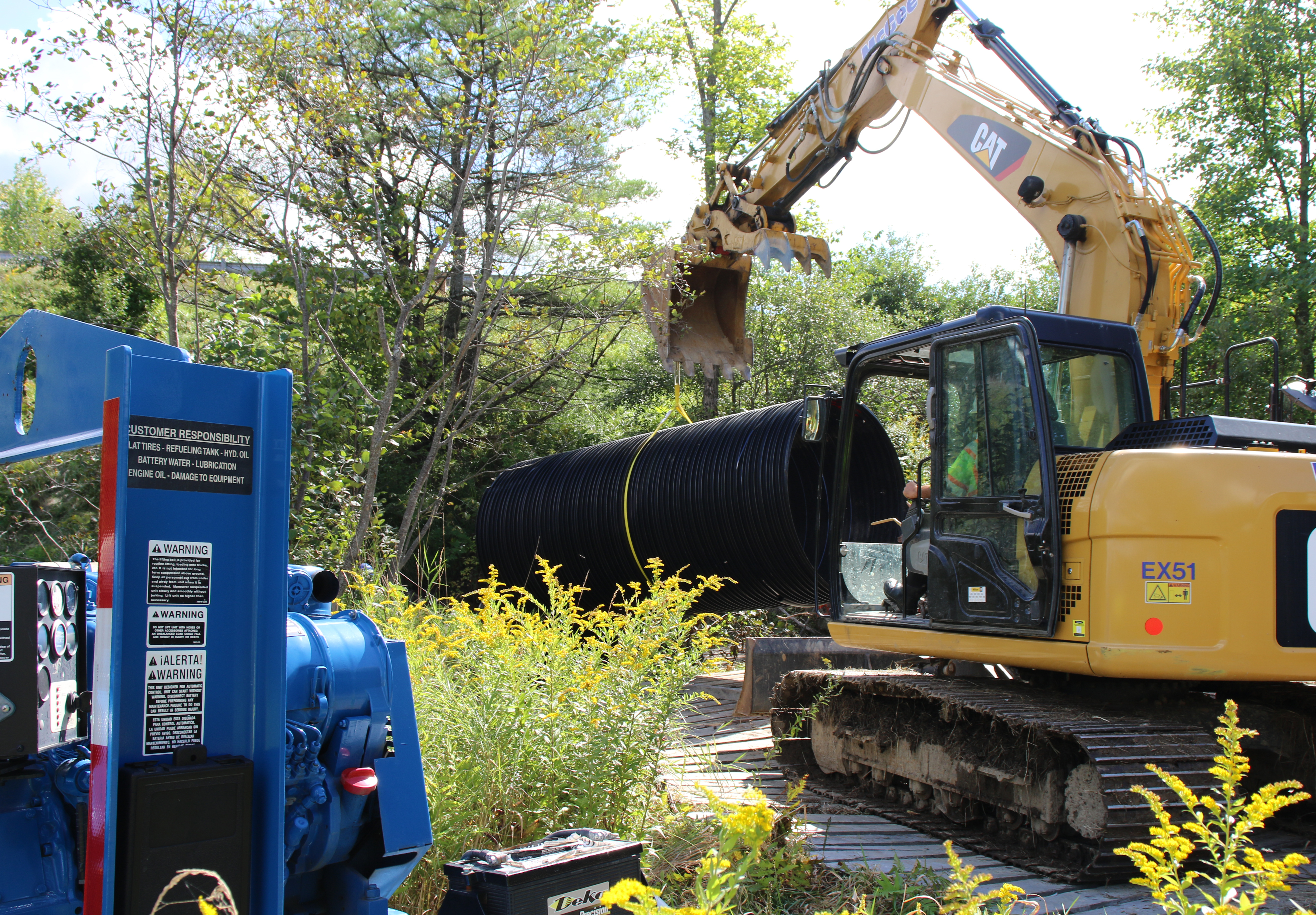 Backhoe pulling a culvert with a slip line