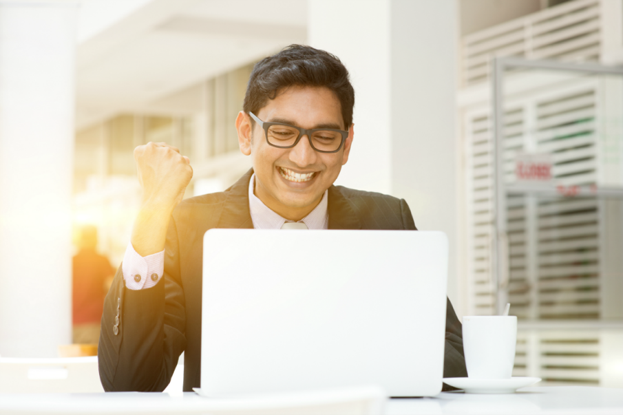 Man looking at his laptop with an excited expression | SupportingStrategiesFranchise.com