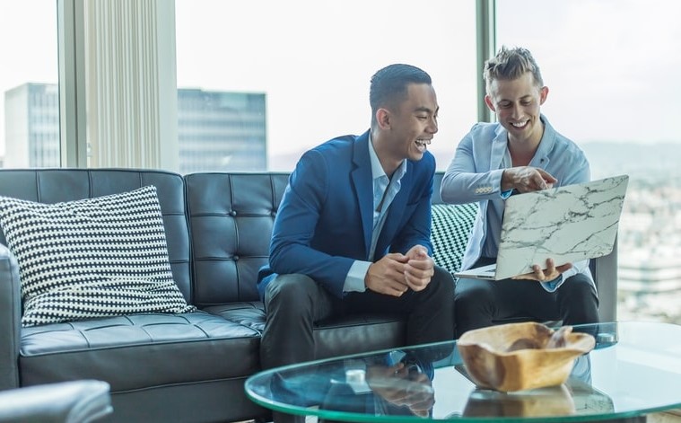 Two Businessmen Looking at Laptop and Smiling | SupportingStrategiesFranchise.com