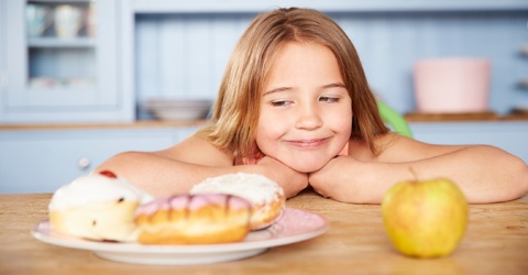 Girl choosing between healthy snack and unhealthy snack