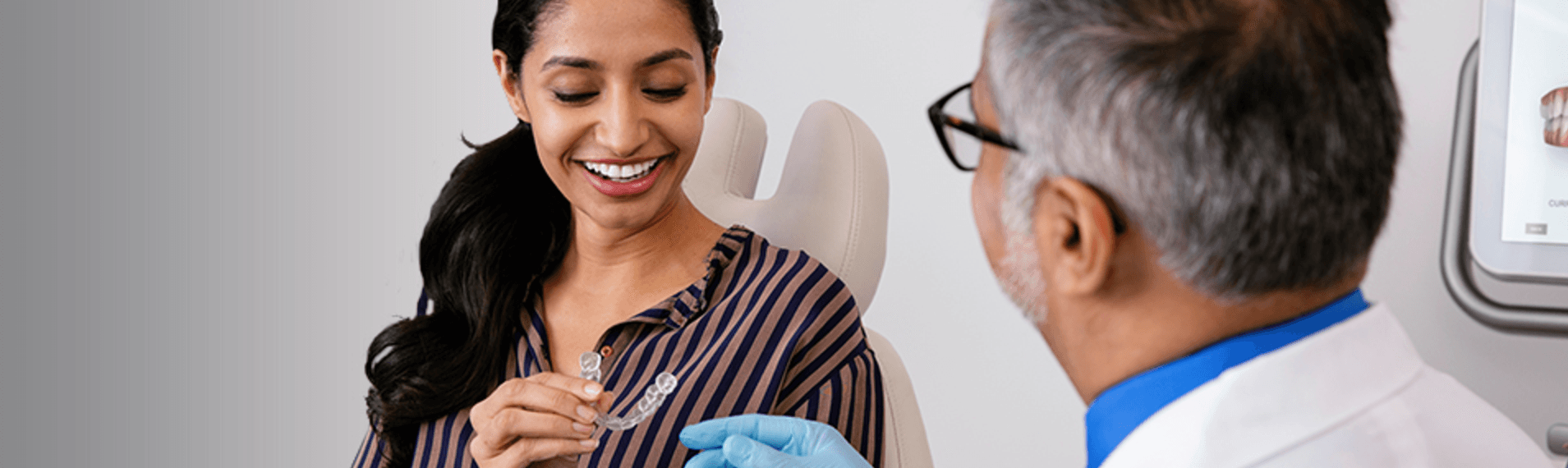 Woman Holding Invisalign Aligner in Dental Chair