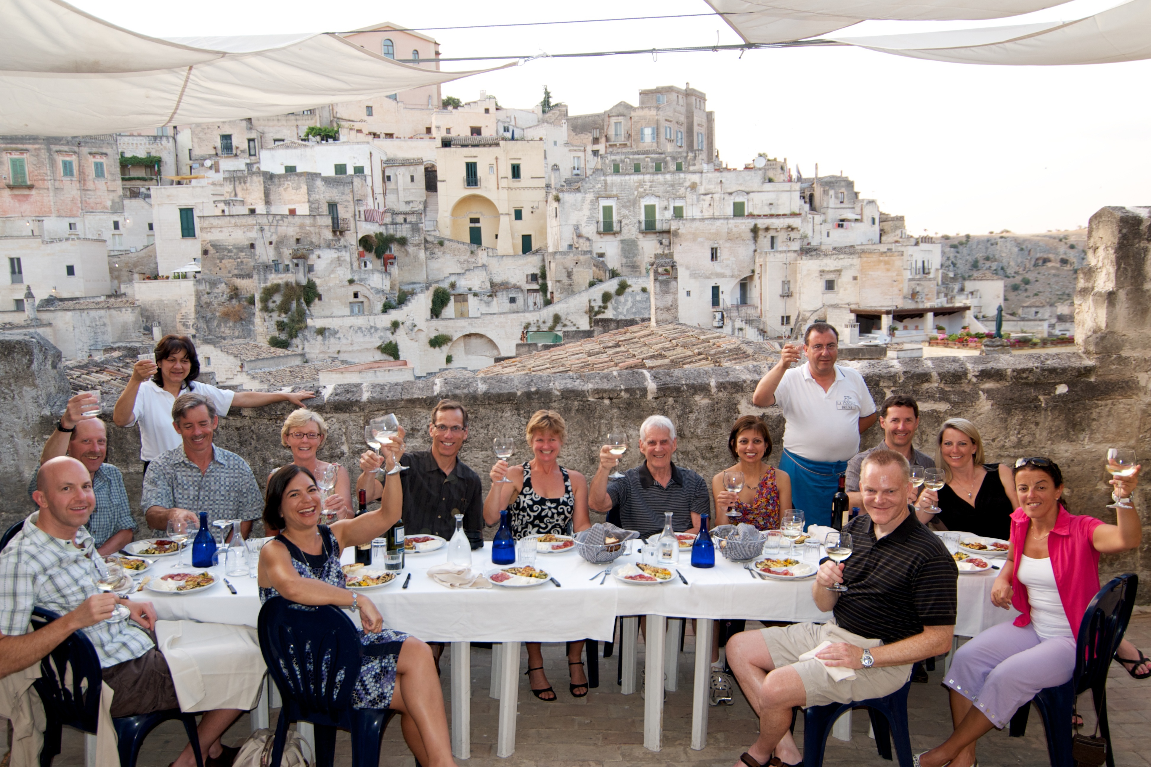 A photograph of a group of cyclists enjoying dinner in Italy. 