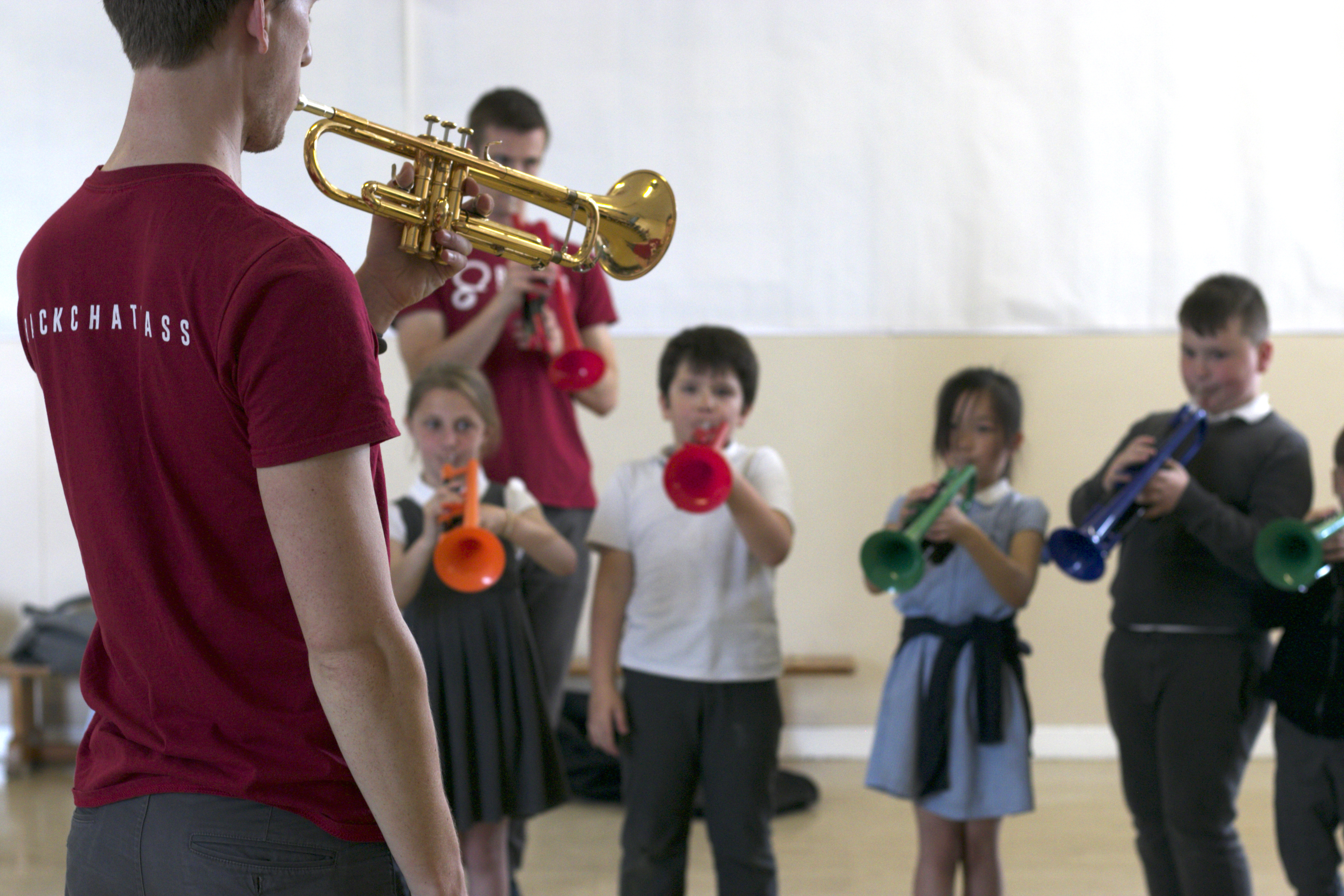 A brass tutor leading a session with young children.