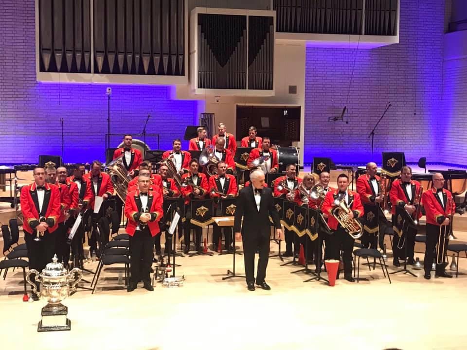 A brass band and conductor on stage.