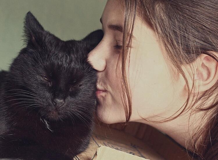 une jeune fille embrasse un chat noir