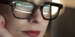 Woman in glasses looking at the code
