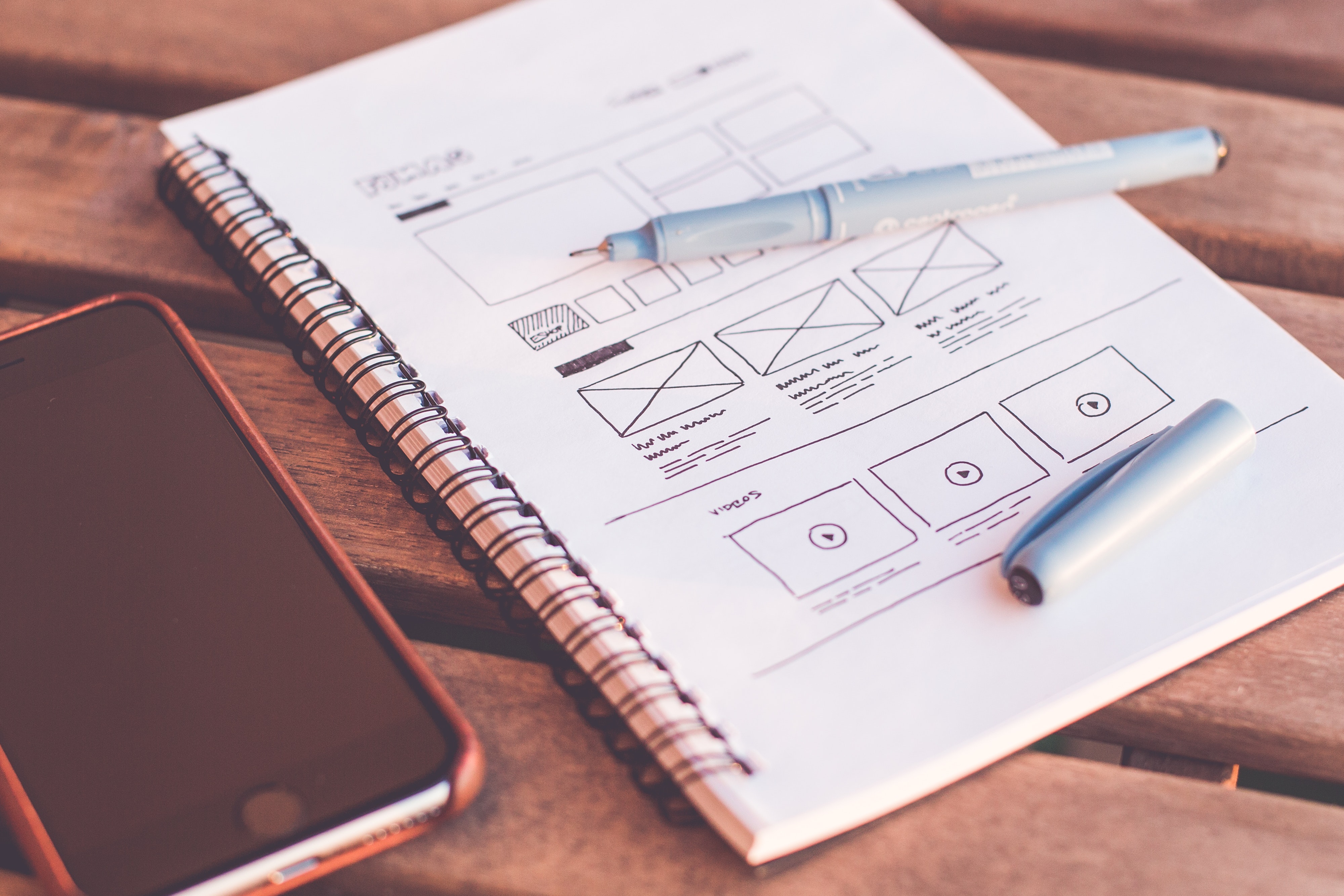 Notebook beside iPhone on wooden table
