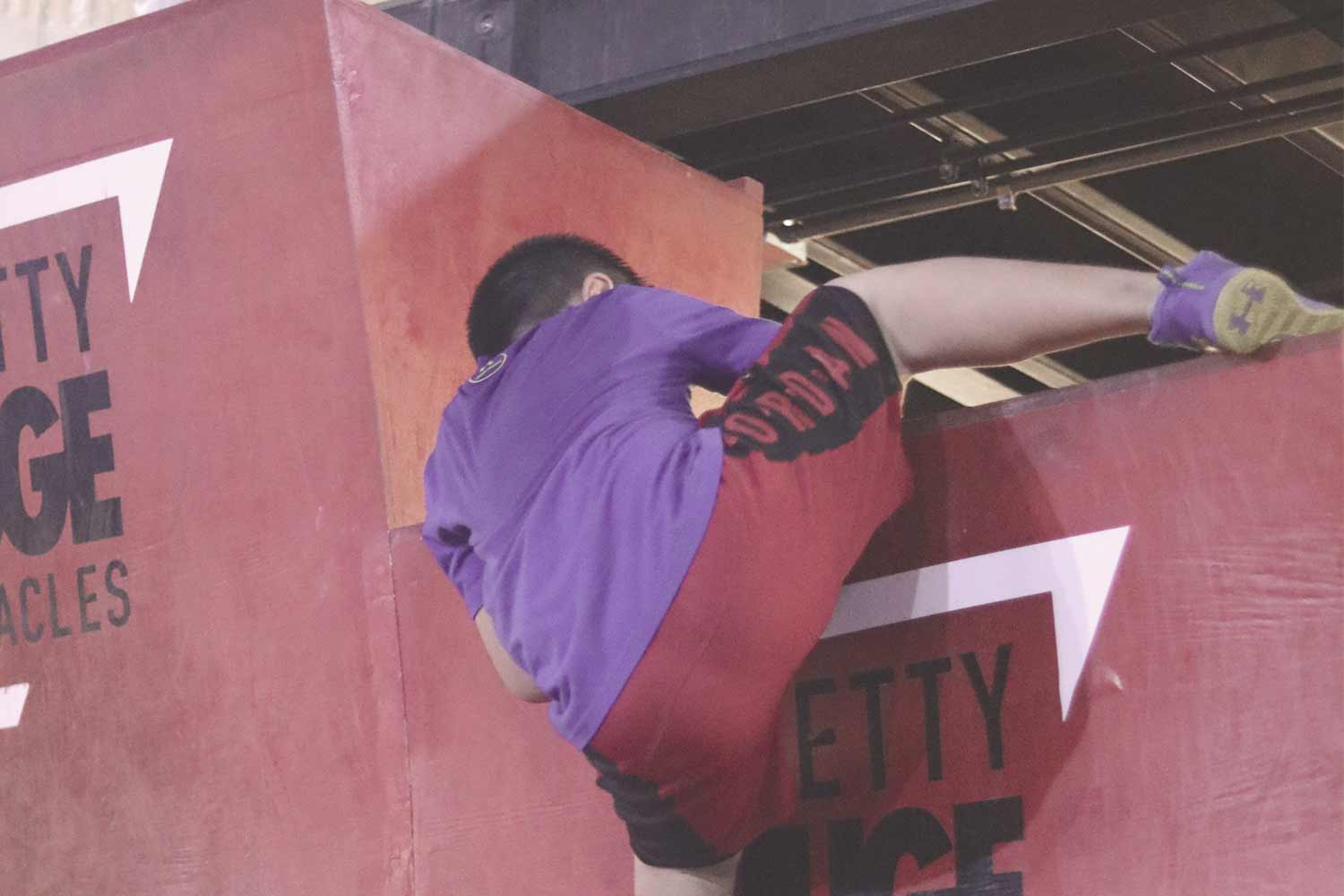 Boy climbing up warped wall at PHO during a training session