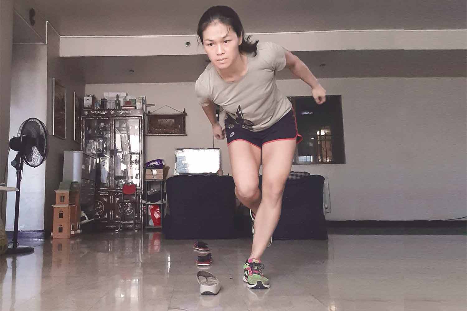 Woman doing exercises at home with shoes as obstacles