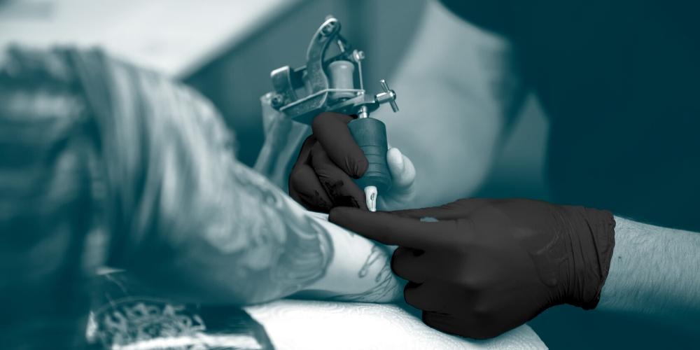 Unigloves black nitrile gloves being used by a tattoo artist.