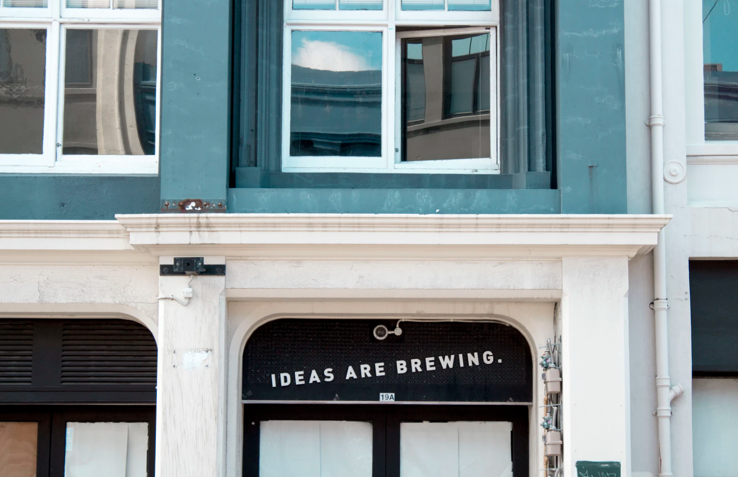 front of a building with a sign on a door that reads "ideas are brewing"