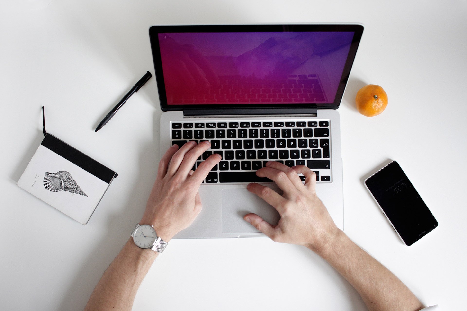 laptop on desk with pen and phone