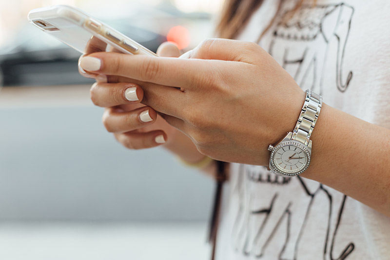 Woman holding mobile phone in both hands and texting