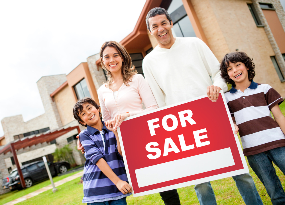 Happy family holding poster of a house for sale