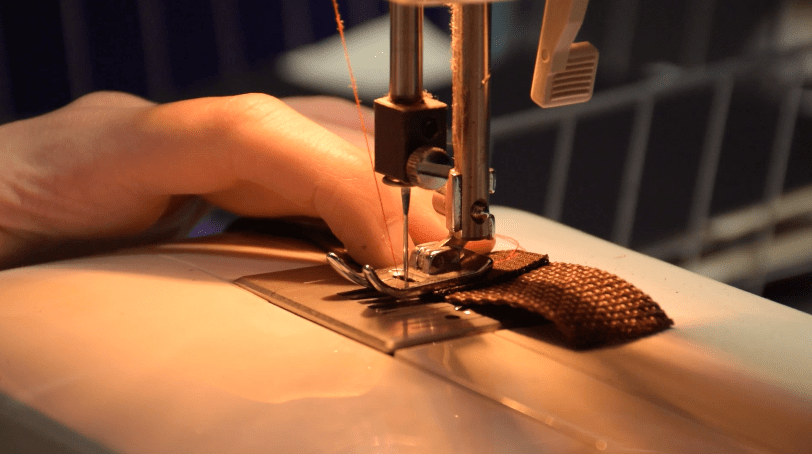 Cosplayer sewing elastic to woven nylon for armor straps