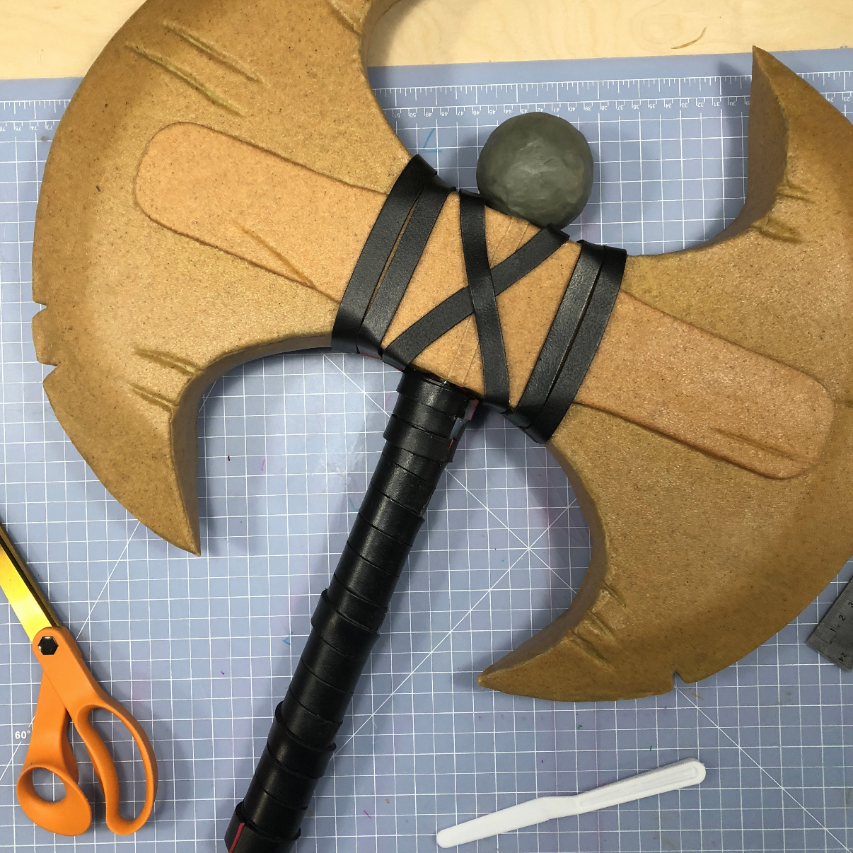 Finished cosplay axe covered in tan Worbla thermoplastic with strap details