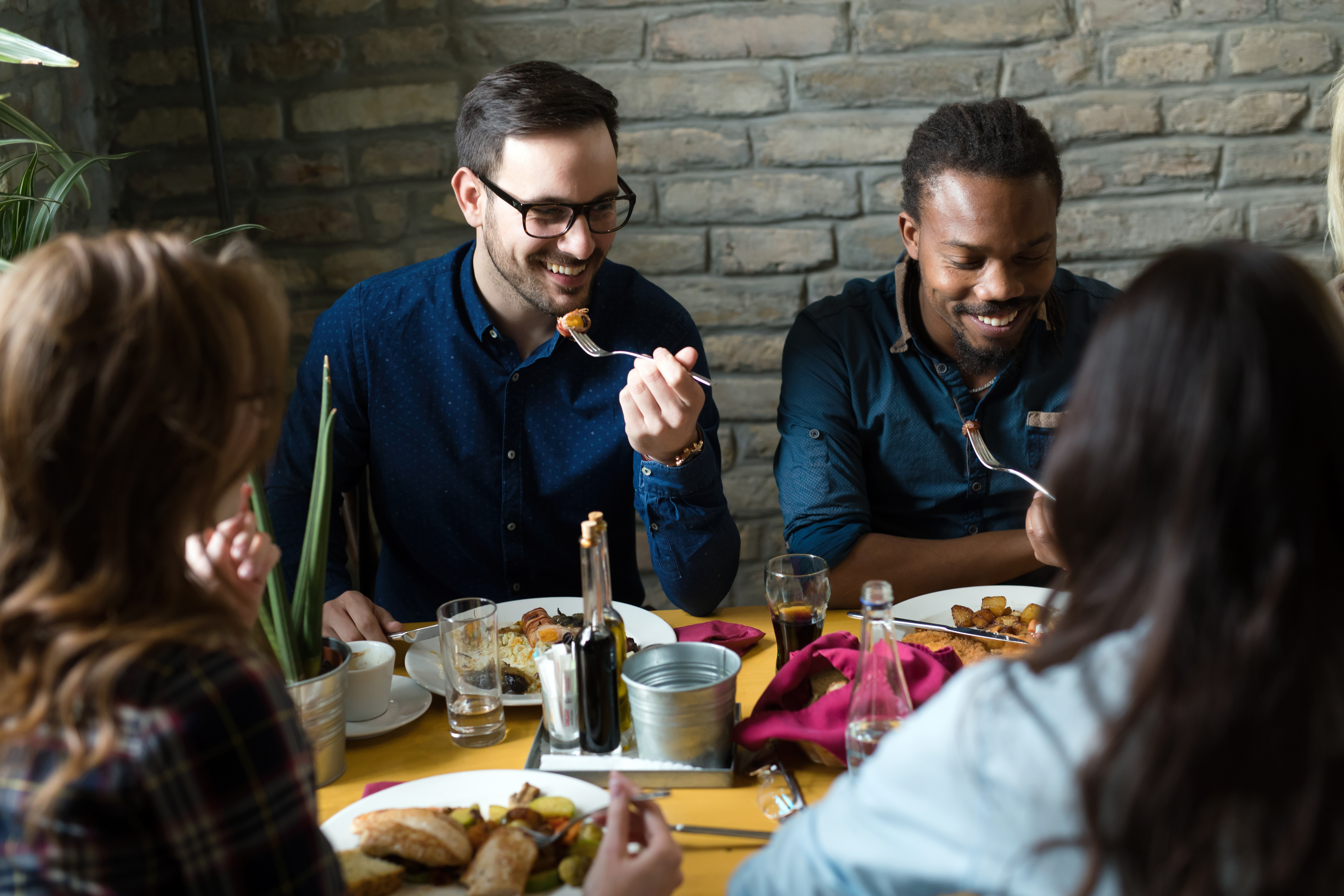 Canva - Group of happy business people eating together in restaurant