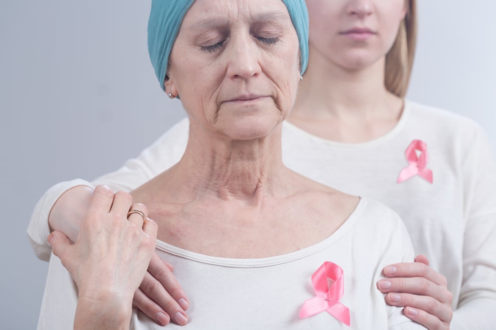 Cancer woman and young girl with pink ribbon, embracing