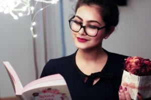 A girl wearing glasses as she reads and holds a present