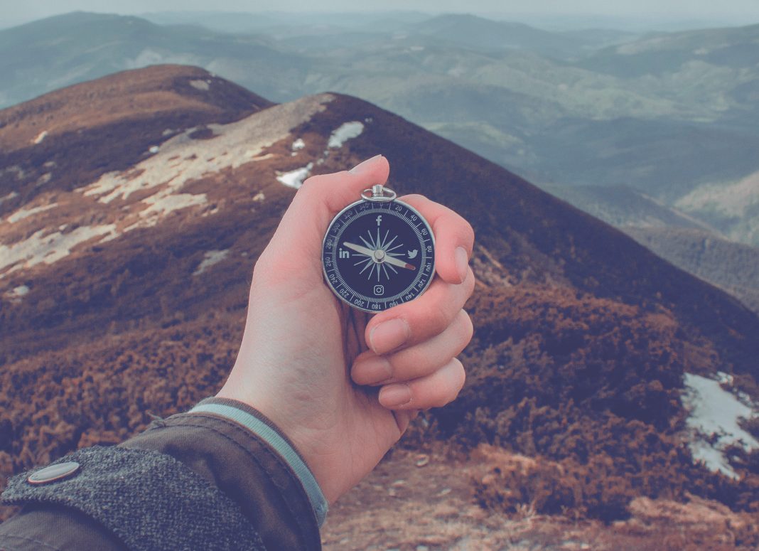 brujula-montaña-paisaje-mano