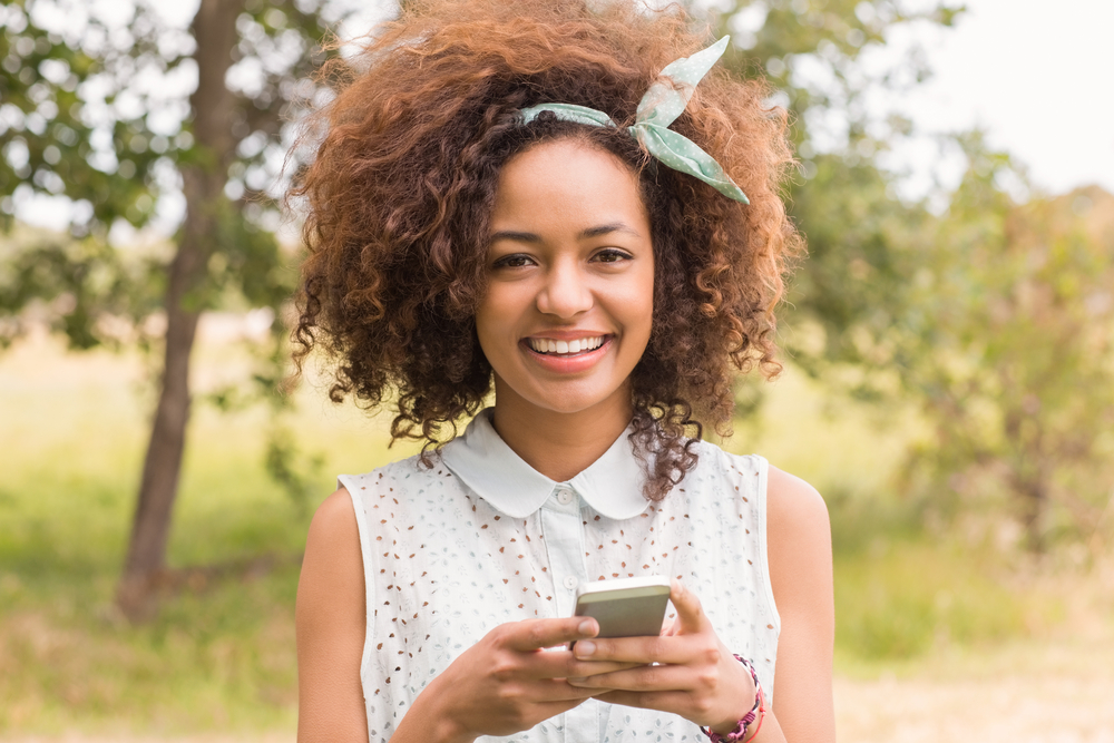 Happy young woman using smartphone on a sunny day