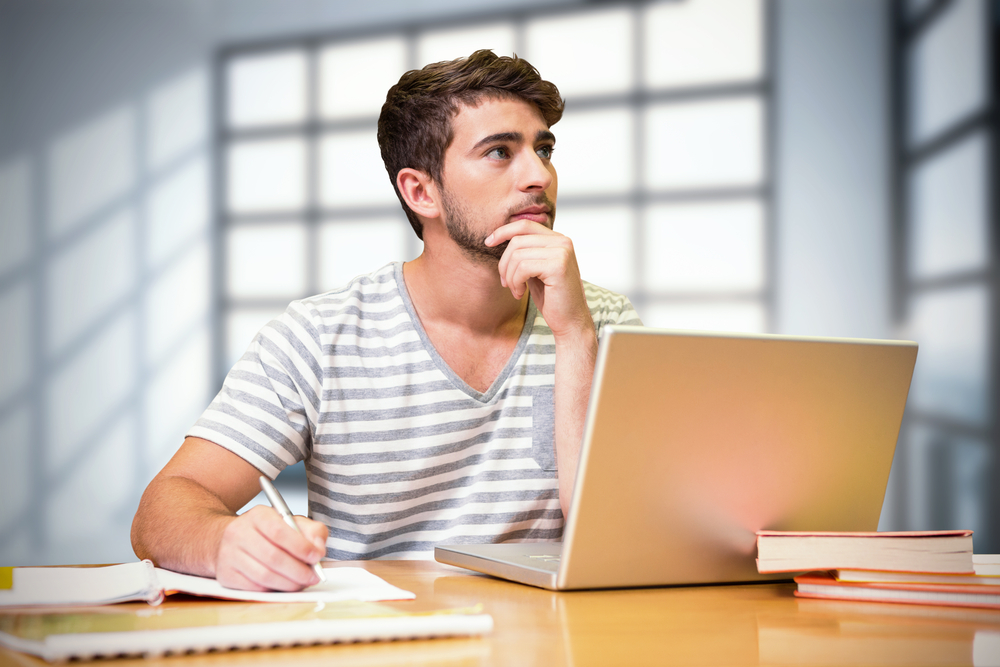 Student studying in the library with laptop against room with large windows showing city